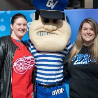 Two alumnae pose with Louie the Laker at the Detroit Red Wings GVSU Night
